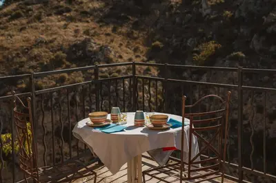 a table with cups and plates of food on a balcony at Le Tamaroque in Portel-des-Corbières