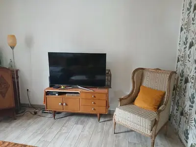 a living room with a tv on a dresser and a chair at Mas cantecou in Mosset