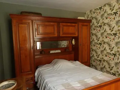 a bed in a bedroom with a wooden cabinet at Mas cantecou in Mosset