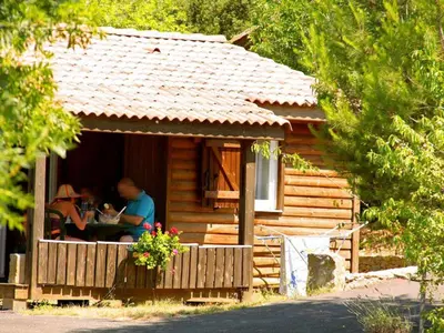 a man and woman sitting at a table in a cabin at Chalet Confort avec Terrasse - 4 Personnes - API-1-52-1742 in Villegly