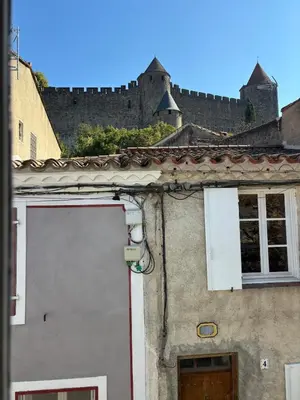 a building with a door and a castle in the background at La Lodge des Remparts View and Private Patio in Carcassonne