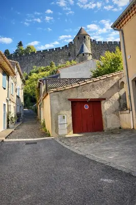 an alley with a building with a red door at La Lodge des Remparts View and Private Patio in Carcassonne