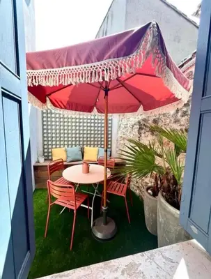 a table and chairs under an umbrella on a balcony at La Lodge des Remparts View and Private Patio in Carcassonne