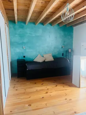 a bedroom with a bed and a blue wall at Las Mijeannos in Cazalrenoux