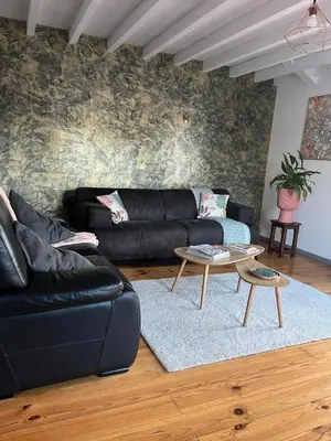 a living room with a black leather couch and a table at Las Mijeannos in Cazalrenoux