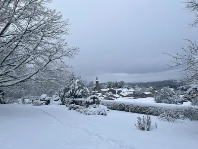 a snow covered yard with a house and trees at Maison de village, Route des lacs in Le Bez
