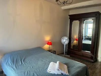 a bedroom with a bed and a mirror and a fan at Spacious house in the center of Quillan in Quillan