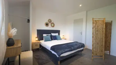 a bedroom with a large bed with blue pillows at Villa Élégance in Peyriac-de-Mer