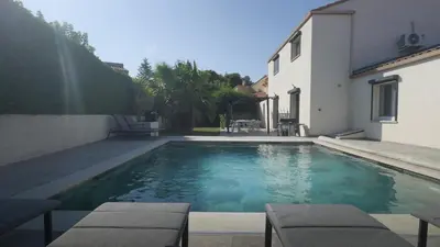 a swimming pool with two chairs and a house at Villa Élégance in Peyriac-de-Mer
