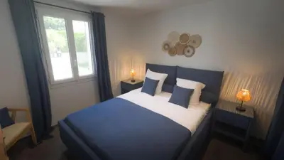 a bedroom with a blue bed with pillows and a window at Villa Élégance in Peyriac-de-Mer