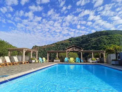 a swimming pool with chairs and a mountain in the background at Maison de vacances, gîte au calme en pleine nature, le Frêne in Lacrouzette
