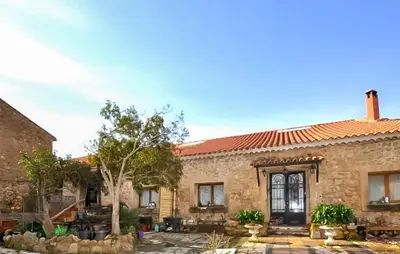 an old stone house with a patio and trees at Maison Piscine Proche Mer in Portel-des-Corbières