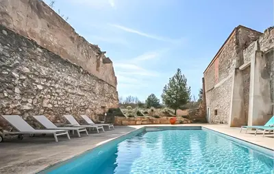 a swimming pool in front of a stone wall at Maison Piscine Proche Mer in Portel-des-Corbières