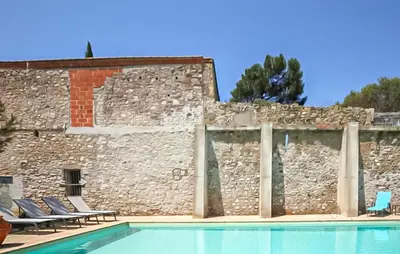 a stone courtyard with trees and a building at Maison Piscine Proche Mer in Portel-des-Corbières