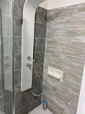 a bathroom with a shower with a tile wall at Maison T4 dans ancien corps de ferme avec lac in Gaudiès