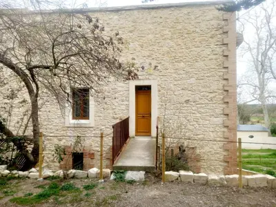 a brick house with a yellow door and a tree at Gite GRENACHE in Sigean