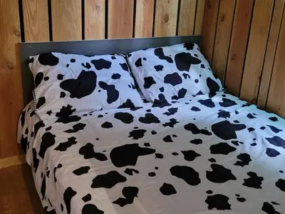 a bed with a black and white blanket with cows on it at Chalet 6 pers avec Terrasse & Jardin - API-1-52-1952 in Pamiers