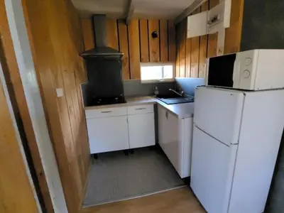 a small kitchen with a stove and a refrigerator at Chalet 6 pers avec Terrasse & Jardin - API-1-52-1952 in Pamiers