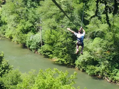 a person on a zip line over a river at Chalet Confortable avec Terrasse - 5 pers - API-1-52-1957 in Pamiers