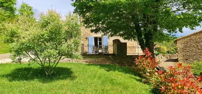 a house with a yard with a tree and grass at L'echappee nature le grand gite in Saint-Benoît