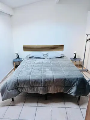 a bedroom with a large bed with two tables at Maison de village à Roquefort des Corbières in Roquefort-des-Corbières