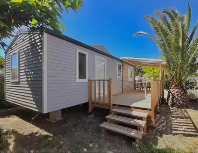 a tiny house with a porch and a deck at Mobil-home camping Port-la-nouvelle in Port-la-Nouvelle