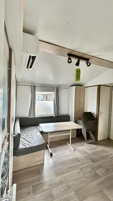 a caravan with a bed and a table in a room at Mobil-home camping Port-la-nouvelle in Port-la-Nouvelle