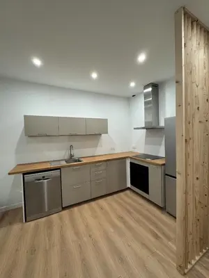 a kitchen with stainless steel appliances and wooden floors at T2 centre-ville rénové avec goût in Narbonne