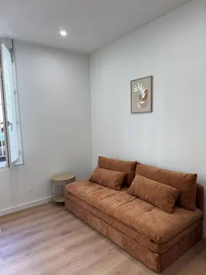 a brown couch in a living room with white walls at T2 centre-ville rénové avec goût in Narbonne