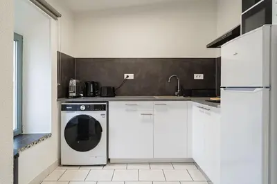 a kitchen with a washing machine in a white kitchen at Le Calme des Jacobins Centre de Narbonne in Narbonne