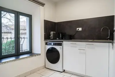 a kitchen with a washing machine and a window at Le Calme des Jacobins Centre de Narbonne in Narbonne