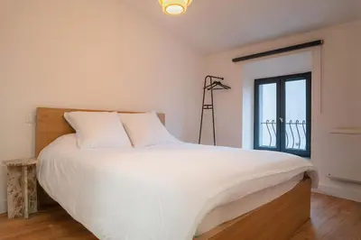a bedroom with a large white bed and a window at Le Calme des Jacobins Centre de Narbonne in Narbonne