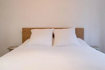 a bed with white sheets and two pillows at Le Calme des Jacobins Centre de Narbonne in Narbonne
