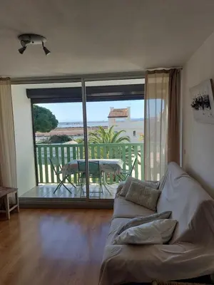 a living room with a couch and a view of a balcony at Le Grand Large in Gruissan