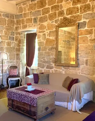 a bedroom with a bed and a stone wall at Le Castillou in Luc-sur-Aude