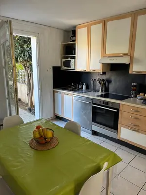a kitchen with a table with a bowl of fruit on it at Fleur de sel in Gruissan