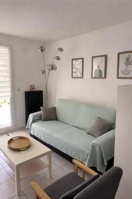 a living room with a green couch and a table at Fleur de sel in Gruissan
