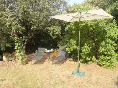 a table and chairs under an umbrella in a yard at La ventaillole in Ventenac-Cabardès