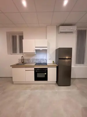 a kitchen with white cabinets and a stainless steel refrigerator at Le Diamant in Narbonne