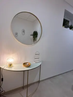 a round mirror on a white wall with a table at Le Diamant in Narbonne