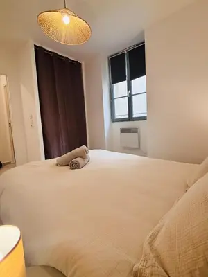 a bedroom with a large white bed and a window at Appartement duplex cœur de ville in Narbonne