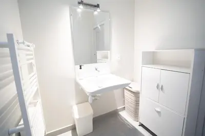 a white bathroom with a sink and a mirror at Air-conditioned 2 bedroom apartment with Terrace Parking Carcassonne in Carcassonne