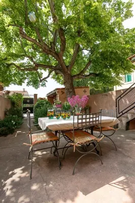 a table and chairs with a tree in a yard at Le Vieux Tilleul - Maison de vacances in Ferrals-lès-Corbières