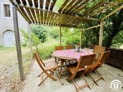 a wooden table and chairs under a pergola at La maison in Davejean