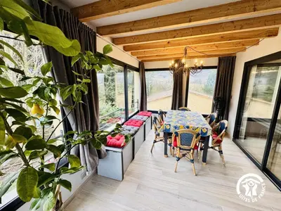 a dining room with a table and chairs and windows at Grand sissou in Bugarach