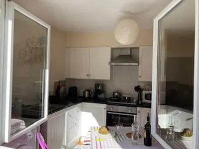 a kitchen with white cabinets and a table with a bottle of wine at Regard du planteur d'arbres in Saint-Paul-de-Fenouillet