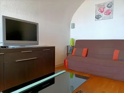 a living room with a couch and a flat screen tv at Appartement charmant avec balcon, piscine - 5 pers. - FR-1-619-159 in Gruissan
