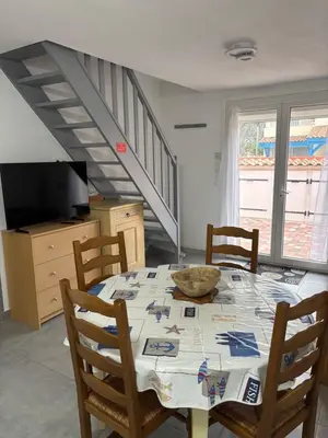 a dining room with a table with chairs and a tv at Clos des pins- Climatisation-Parking-Draps By LCG in Gruissan