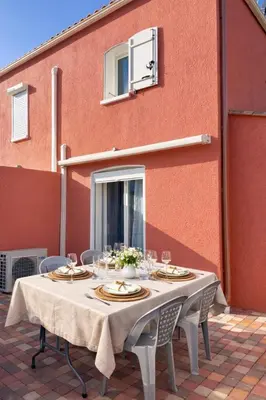 a table with plates and glasses on a patio at Clos des pins- Climatisation-Parking-Draps By LCG in Gruissan