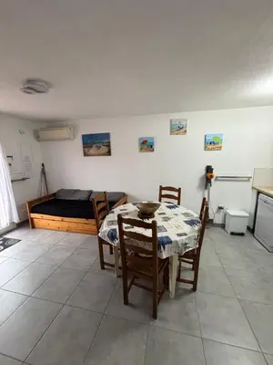 a living room with a table and a bed at Clos des pins- Climatisation-Parking-Draps By LCG in Gruissan